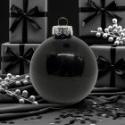 Fényes fekete üveggömb fekete ajándékdobozok és ezüst bogyós dekorációk között (8 cm).