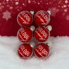 Piros kézzel festett üveg karácsonyi gömb szett „Boldog karácsonyt!” felirattal, havas háttérrel.