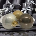 Három Silent Night üvegdísz ajándékdobozok és ezüst dekoráció között, gyöngyházfényű felülettel.