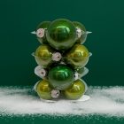 Zöld üveg karácsonyi gömb szett havas dekorációval zöld háttér előtt (12×6 cm).