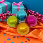 Színes üveg karácsonyi gömbök (világoskék, pink, sárga, zöld) narancssárga és kék dekorációval