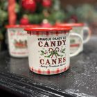 Karácsonyi hangulatú bádog bögre Candy Canes mintával, fekete asztalon, háttérben ünnepi díszekkel.