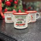 Karácsonyi hangulatú bádog bögre autós mintával, fekete asztalon, háttérben karácsonyi díszekkel.