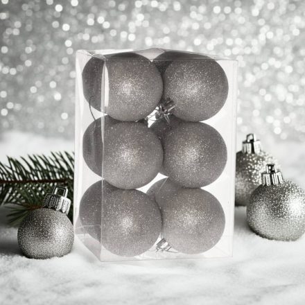 Ezüst glitteres műanyag karácsonyi gömb szett (12×6 cm) átlátszó dobozban, havas felületen, ezüst háttérrel.