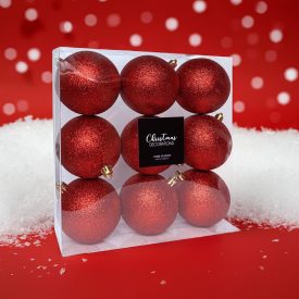 Piros glitteres karácsonyi gömb szett 9 darabos dobozban, ünnepi háttérrel.