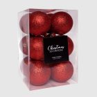 Piros glitteres műanyag karácsonyfadíszek átlátszó dobozban, fehér háttérrel.