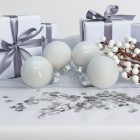 Négy darab fehér üvegdísz fényes és matt felülettel, ezüst szalaggal átkötött ajándékdobozok között (3 cm).