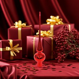 Fényes piros üveg csúcsdísz piros selyem háttér előtt, arany masnis ajándékdobozokkal és piros bogyós ágakkal körülvéve.