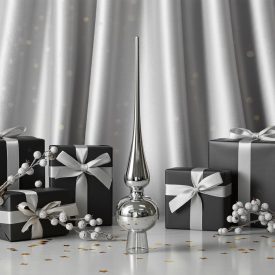 Fényes ezüstszínű üveg csúcsdísz ajándékdobozok és ezüst bogyós ágak között, elegáns ezüst háttér előtt.