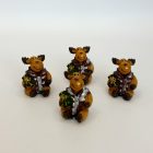 Négy pufi kabátos, ülő rénszarvas figura ajándékkal a kezében, fehér háttéren.