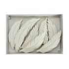 8 darab fehér tollfigura dobozban, részletgazdag mintázattal, felülnézetből.