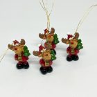 Négy kis rénszarvas figura piros ruhában, zöld fenyőfával és arany akasztóval, fehér háttéren.