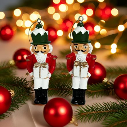 Két diótörő katona figura piros díszek és fenyőágak között, ünnepi fényekkel a háttérben.